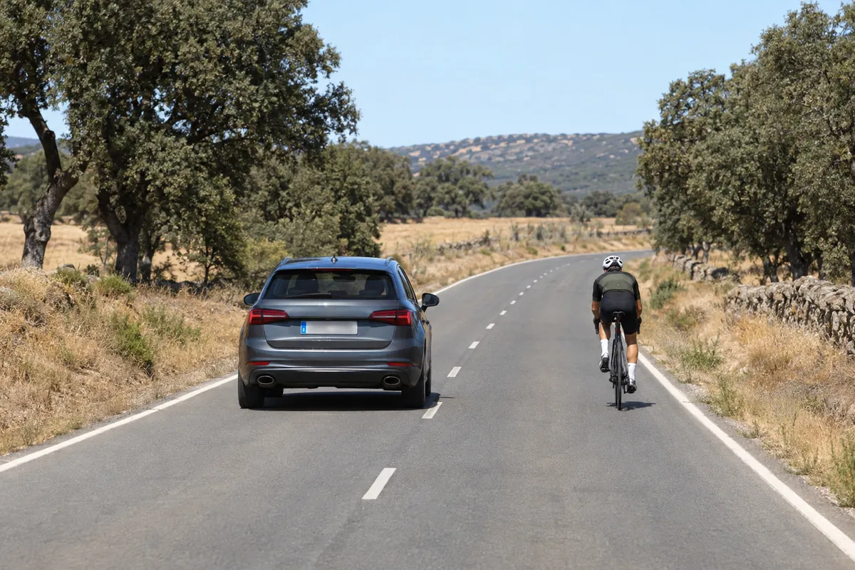 Con un carril por sentido, el coche ocupa parte del carril contrario y deja un hueco ancho al ciclista.
