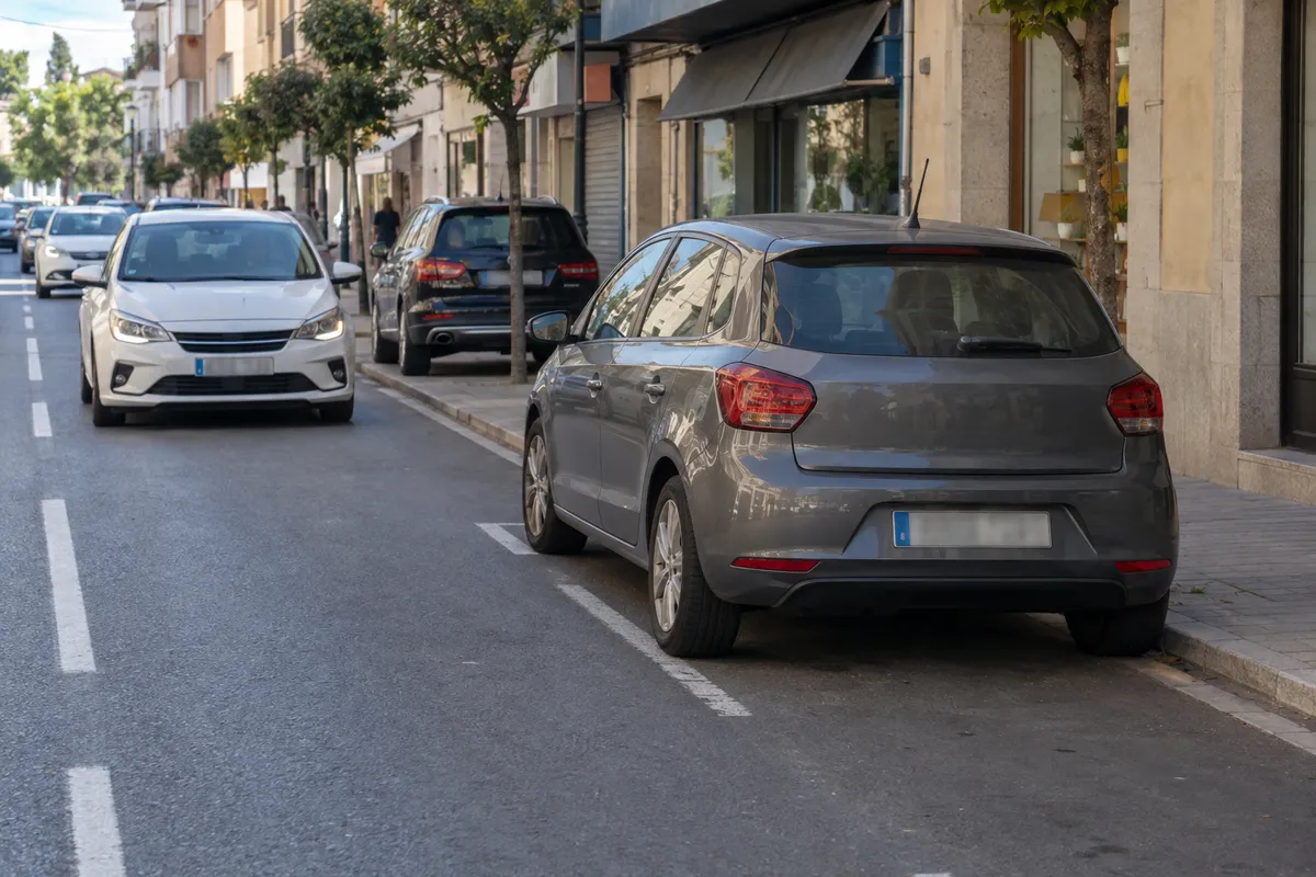 Coche todavía en su plaza en línea, con un turismo cerca que ya circula por el carril.