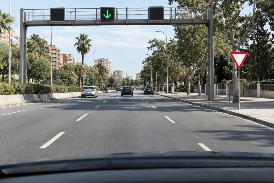 Vista desde el puesto de conducción: un semáforo de carril con una flecha verde sobre el carril y, más adelante, una señal de ceda el paso