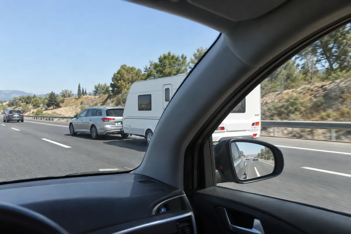 Un coche tira de una caravana por el carril derecho de una autovía.