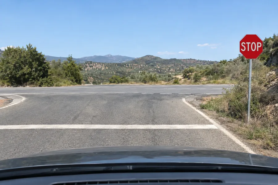 Un coche detenido justo antes de la línea de detención de un stop en un cruce rural