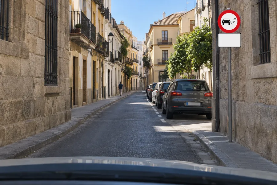 La señal de entrada prohibida según el distintivo ambiental, con su panel complementario debajo, a la entrada de una calle del centro de una ciudad