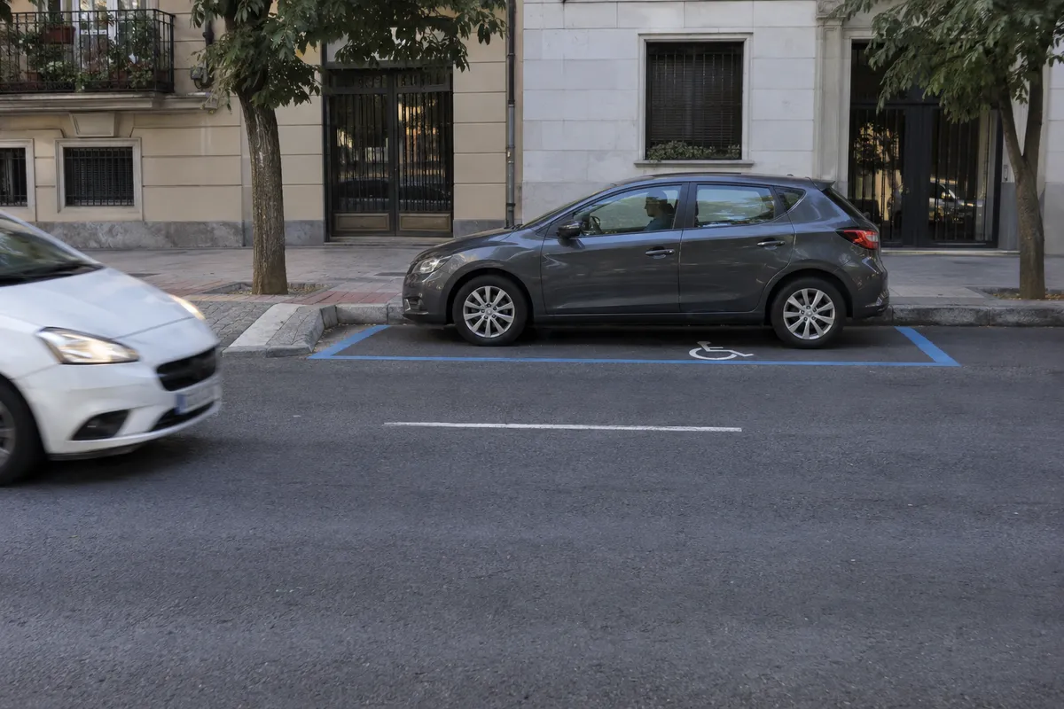 Un conductor permanece al volante en una plaza con la marca de accesibilidad en el suelo.